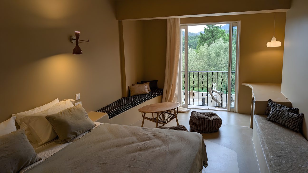 Chambre aux tons sable, banquette sous la fenêtre et balcon ouvert sur la végétation