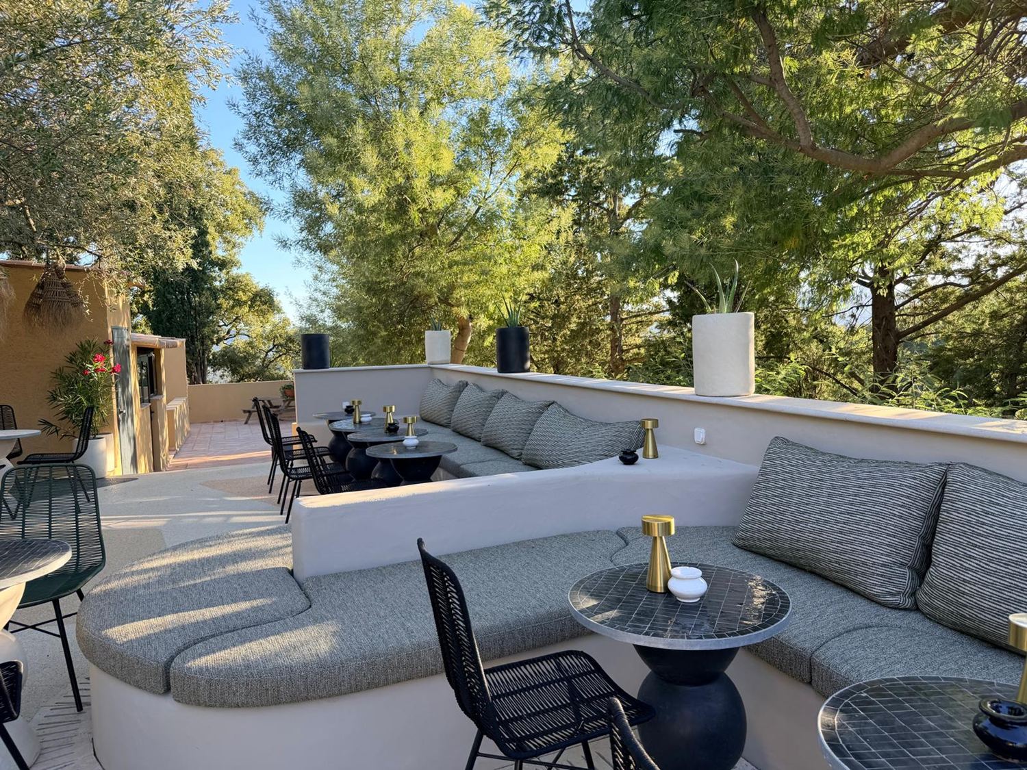 Salon extérieur aux banquettes arrondies sous les arbres