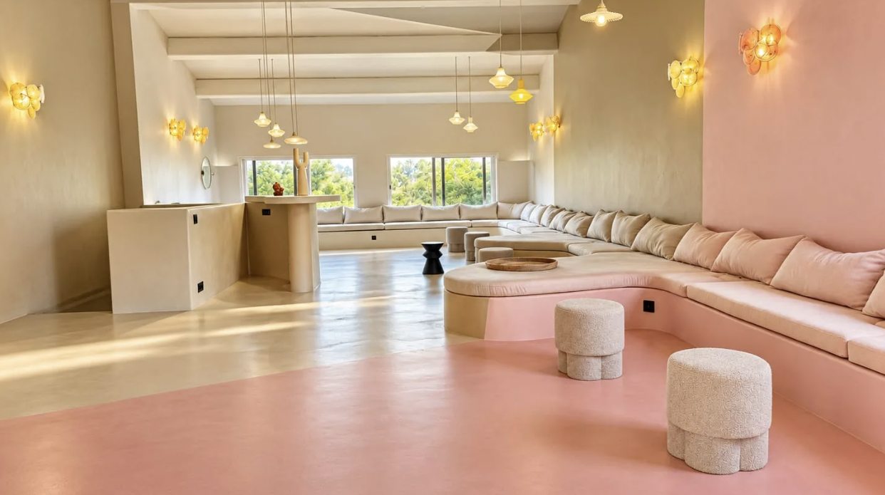 Salle de réception lumineuse au sol rose poudré et longue banquette sculptée