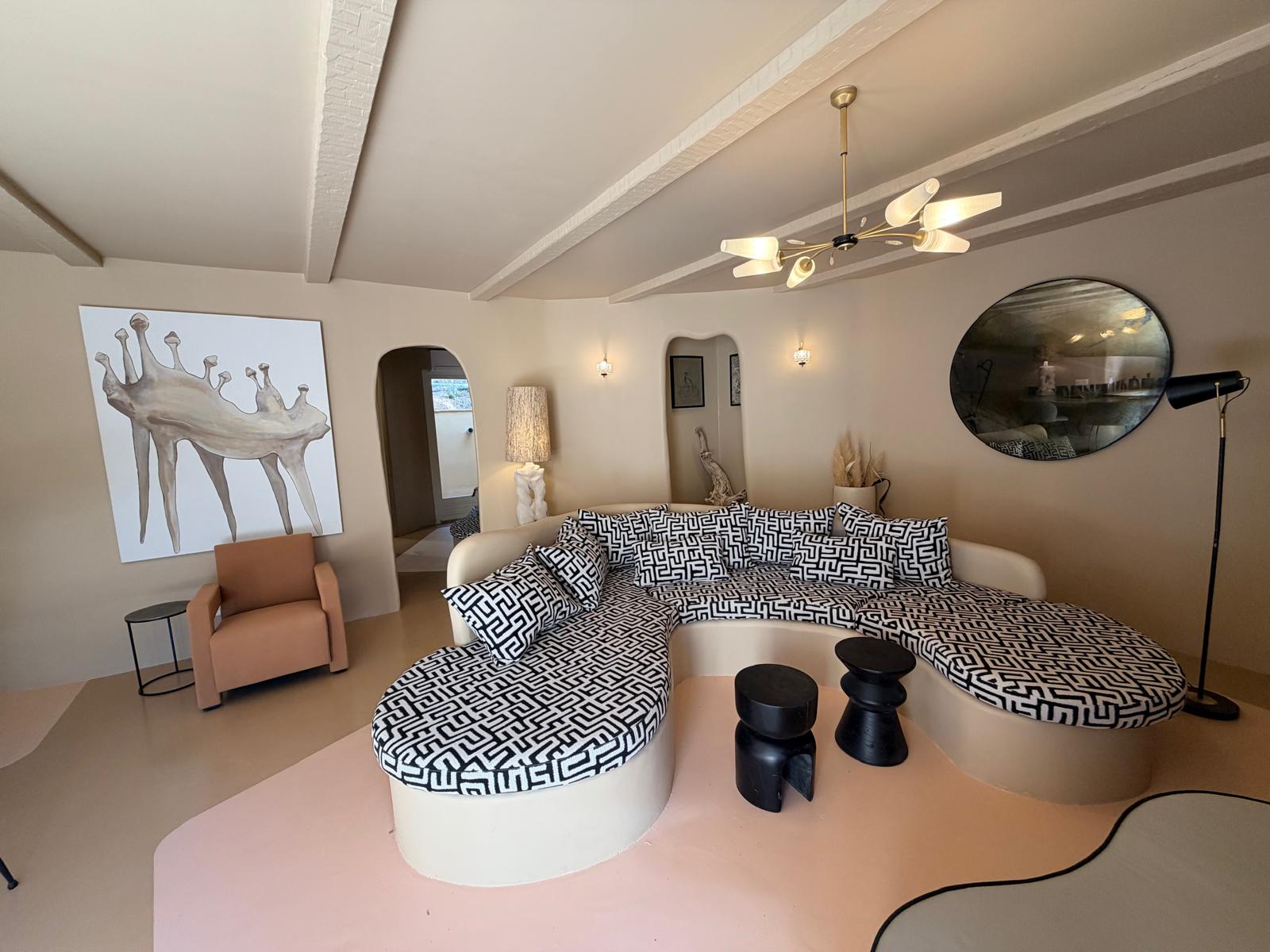 Salon aux banquettes courbes habillées d'un motif graphique noir et blanc, sous une grande toile