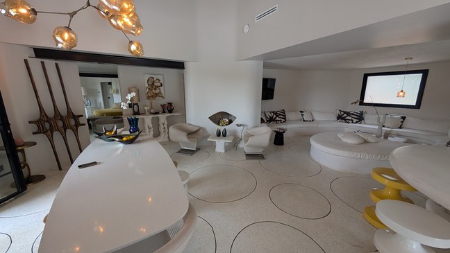Salon blanc aux banquettes arrondies et suspensions en verre